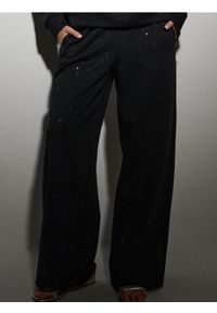 Sinsay - Dresowe spodnie z szeroką nogawką i brokatem - czarny. Kolor: czarny. Materiał: dresówka #1