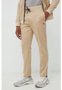 Guess spodnie dresowe męskie kolor beżowy wzorzyste. Kolor: beżowy. Materiał: dresówka