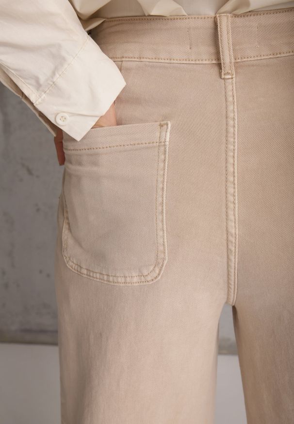 Renee - Beżowe Jeansy High Waist Wide Leg z Bawełny z Naszytymi Kieszonkami Yrelelin. Okazja: na co dzień. Stan: podwyższony. Kolor: beżowy. Długość: krótkie. Wzór: aplikacja. Styl: casual
