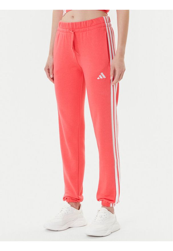 Adidas - adidas Spodnie dresowe Essentials 3-Stripes KE4387 Koralowy Regular Fit. Kolor: pomarańczowy. Materiał: bawełna