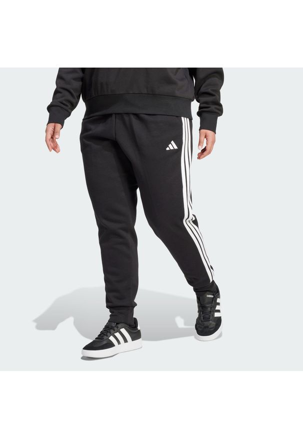 Adidas - Spodnie Essentials 3-Stripes Fleece Slim (Plus Size). Kolekcja: plus size. Kolor: czarny, wielokolorowy, biały. Materiał: polar. Sport: fitness