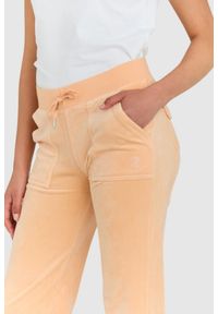 Juicy Couture - JUICY COUTURE Klasyczne welurowe spodnie dresowe del ray w brzoskwiniowym kolorze. Kolor: pomarańczowy. Materiał: dresówka, welur