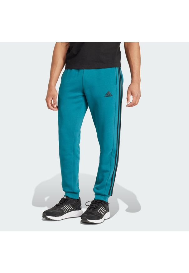 Adidas - Spodnie Essentials Fleece 3-Stripes Tapered Cuff. Kolor: niebieski. Materiał: materiał, polar