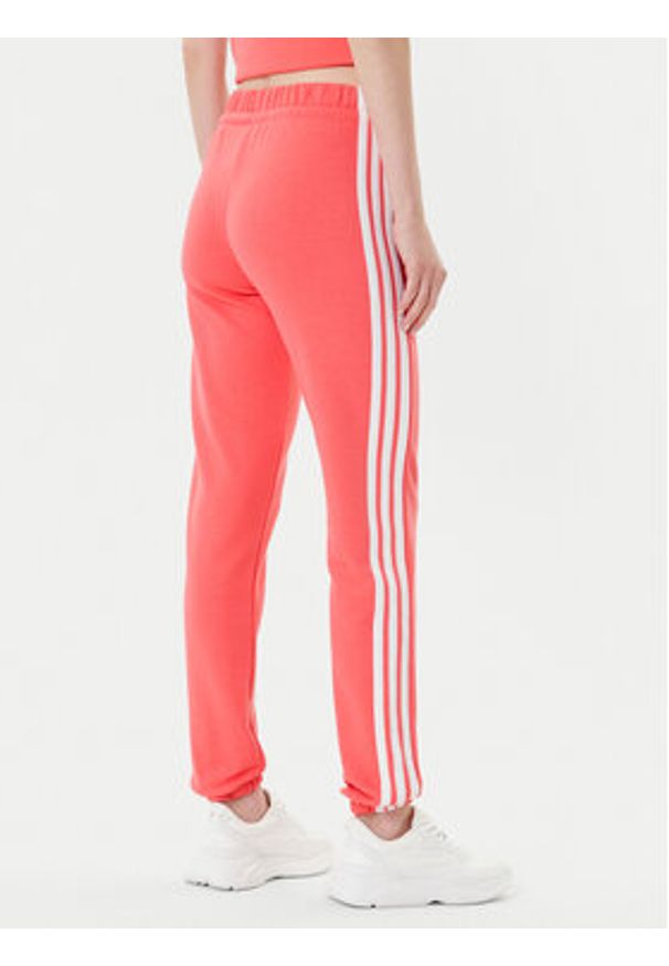 Adidas - adidas Spodnie dresowe Essentials 3-Stripes KE4387 Koralowy Regular Fit. Kolor: pomarańczowy. Materiał: bawełna
