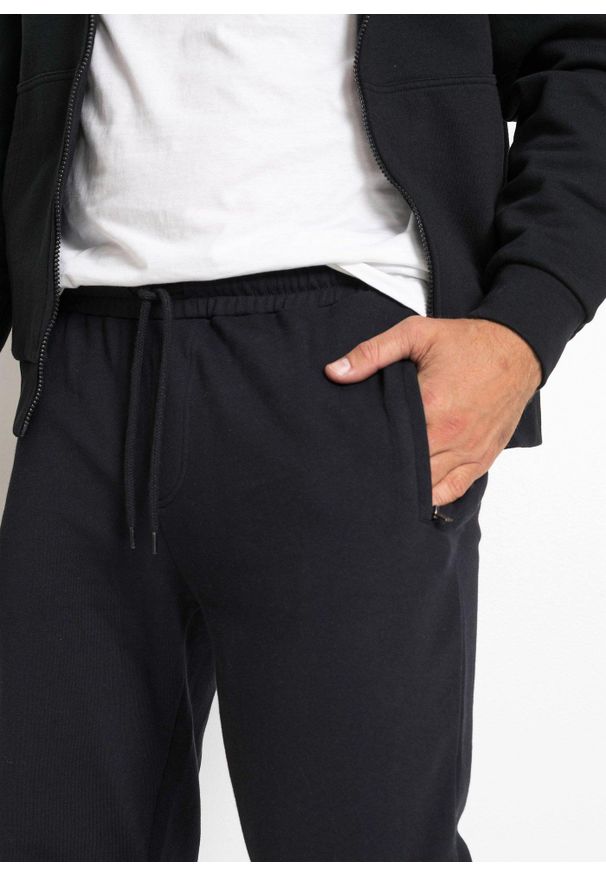 bonprix - Spodnie do biegania z praktycznymi kieszeniami zapinanymi na zamek. Kolor: czarny. Styl: sportowy