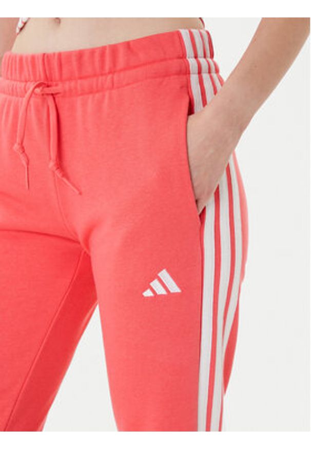 Adidas - adidas Spodnie dresowe Essentials 3-Stripes KE4387 Koralowy Regular Fit. Kolor: pomarańczowy. Materiał: bawełna