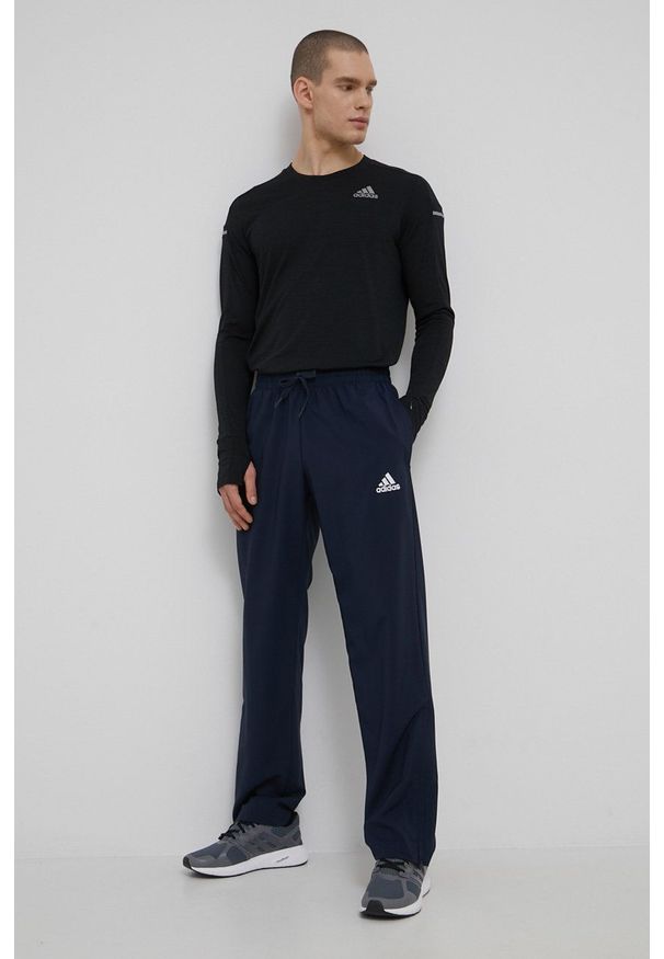 Adidas - adidas spodnie męskie kolor granatowy z nadrukiem. Kolor: niebieski. Materiał: materiał, poliester, skóra. Wzór: nadruk. Sport: fitness