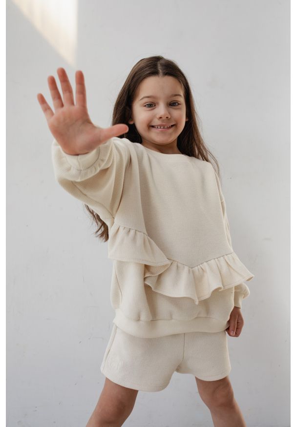 Marsala - MINI bluza oversize z falbanką z dzianiny waflowej w kolorze BRIGHT BEIGE - ANGEL-80-86 (12-18). Kolor: beżowy. Materiał: dzianina. Długość rękawa: długi rękaw. Długość: długie. Wzór: gładki, haft