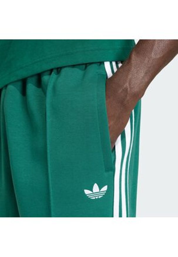Adidas - adidas Spodnie dresowe adicolor Spacer Track KD4088 Zielony Baggy Fit. Kolor: zielony. Materiał: bawełna. Sport: turystyka piesza