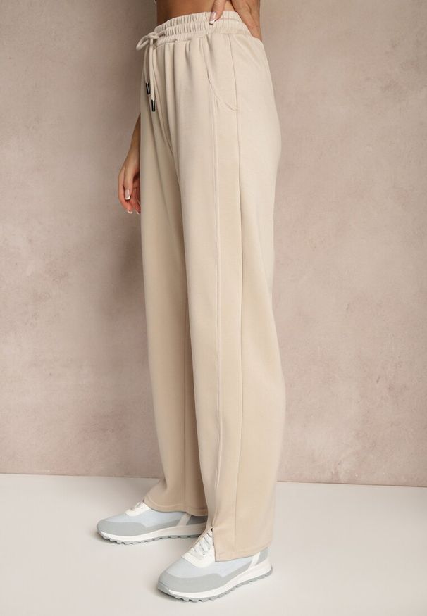 Renee - Beżowe Szerokie Spodnie Dresowe High Waist Ozdobione Sznurkiem Haliran. Okazja: na spacer, na co dzień. Stan: podwyższony. Kolor: beżowy. Materiał: dresówka. Wzór: aplikacja. Styl: elegancki, casual