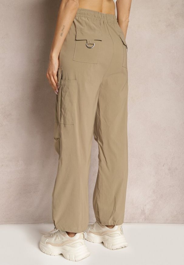 Renee - Ciemnobeżowe Szerokie Spodnie High Waist w Stylu Bojówek Wykończone Gumką w Talii Ellcara. Okazja: na co dzień. Stan: podwyższony. Kolor: beżowy. Materiał: satyna. Wzór: moro. Styl: elegancki, sportowy, militarny, wizytowy, casual