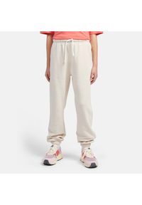 Spodnie dziecięce New Balance LAKG0058LIN – beżowe. Kolor: beżowy. Materiał: bawełna, poliester, dresówka