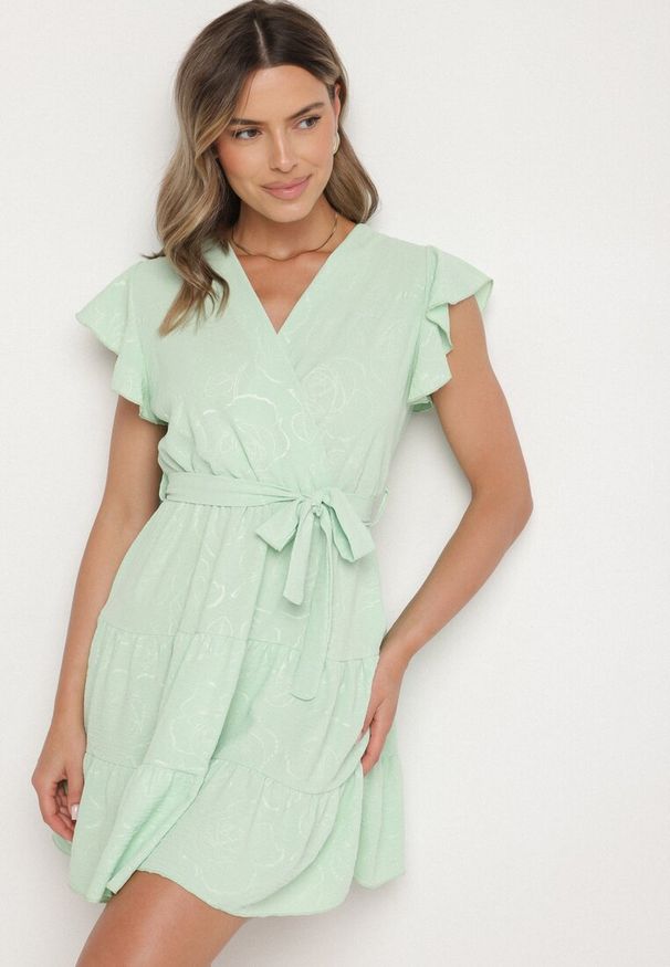 Born2be - Jasnozielona Kopertowa Sukienka Ozdobiona Falbanami i Paskiem Liliessa. Okazja: na co dzień. Typ kołnierza: dekolt w kształcie V. Kolor: zielony. Wzór: aplikacja. Typ sukienki: kopertowe. Styl: klasyczny, casual, elegancki
