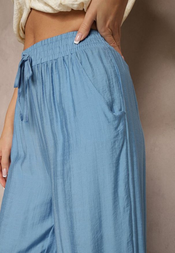 Renee - Niebieskie Spodnie Typu Palazzo o Szerokim Kroju High Waist Ozdobione Wiązaniem Yaslevia. Okazja: na co dzień. Stan: podwyższony. Kolor: niebieski. Wzór: aplikacja. Styl: casual, elegancki