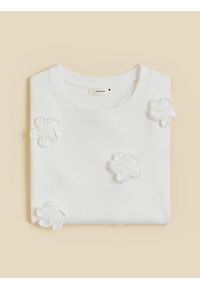 Reserved - T-shirt z kwiatową aplikacją - złamana biel. Materiał: dzianina, bawełna. Wzór: kwiaty, aplikacja