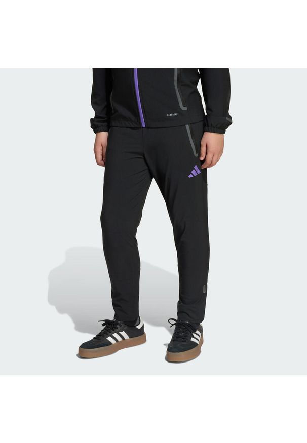 Adidas - Spodnie Manchester United Tiro 25 Competition Vis Tech Travel Kids. Kolor: fioletowy, wielokolorowy, czarny. Sport: piłka nożna