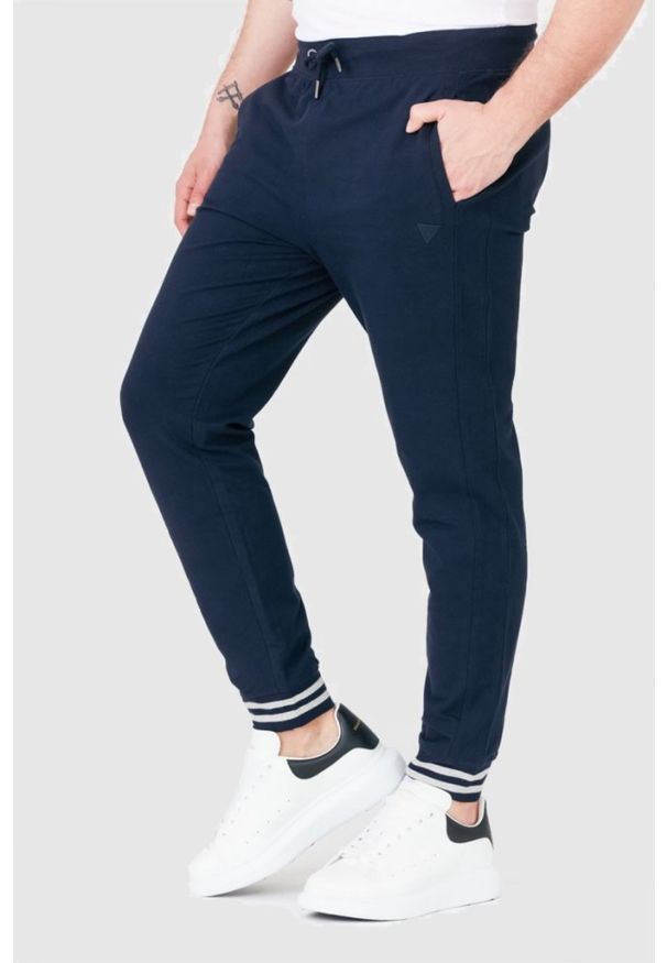 Guess - GUESS Granatowe męskie spodnie dresowe, Rozmiar XL. Kolor: niebieski. Materiał: bawełna, dresówka. Wzór: aplikacja