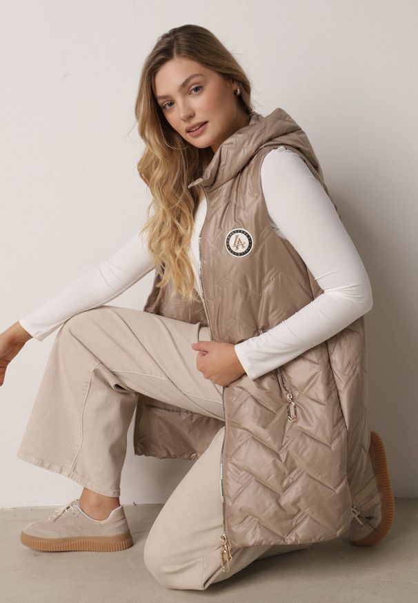 Born2be - Brązowa Przejściowa Kamizelka Pikowana o Długim Kroju z Kapturem i Naszywką Harmaste. Okazja: na co dzień. Typ kołnierza: kaptur. Kolor: brązowy. Materiał: jeans. Długość: długie. Wzór: aplikacja. Styl: casual