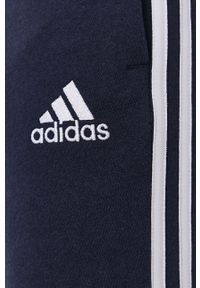 Adidas - adidas Spodnie męskie kolor granatowy gładkie. Kolor: niebieski. Materiał: dzianina, poliester. Wzór: gładki