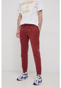 Superdry Spodnie męskie kolor bordowy gładkie. Kolor: czerwony. Materiał: dzianina. Wzór: gładki