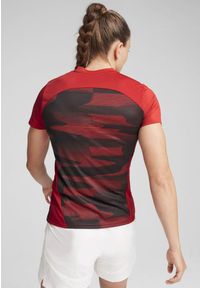 Puma - Damska koszulka przedmeczowa z krótkim rękawem AC Milan PUMA. Kolor: czerwony, czarny, wielokolorowy. Długość rękawa: krótki rękaw. Długość: krótkie