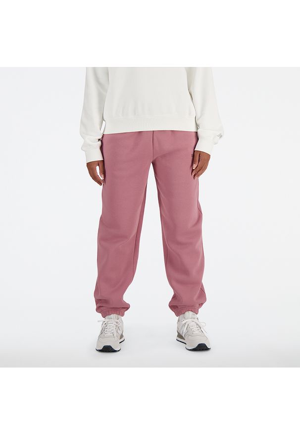 Spodnie damskie New Balance WP41508RSE – różowe. Kolor: różowy. Materiał: poliester, materiał, dresówka, bawełna. Wzór: napisy