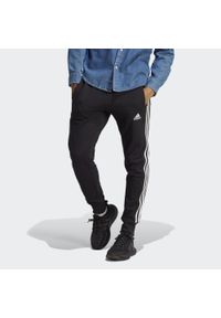 Adidas - Essentials French Terry Tapered Cuff 3-Stripes Pants. Kolor: biały, czarny, niebieski, wielokolorowy. Materiał: dresówka