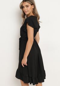 Born2be - Czarna Kopertowa Sukienka z Asymetrycznym Dołem Ozdobiona Falbanką z Paskiem w Talii Snidia. Okazja: na spacer, na co dzień. Kolor: czarny. Wzór: aplikacja. Sezon: lato. Typ sukienki: kopertowe, asymetryczne. Styl: casual, elegancki, klasyczny #4