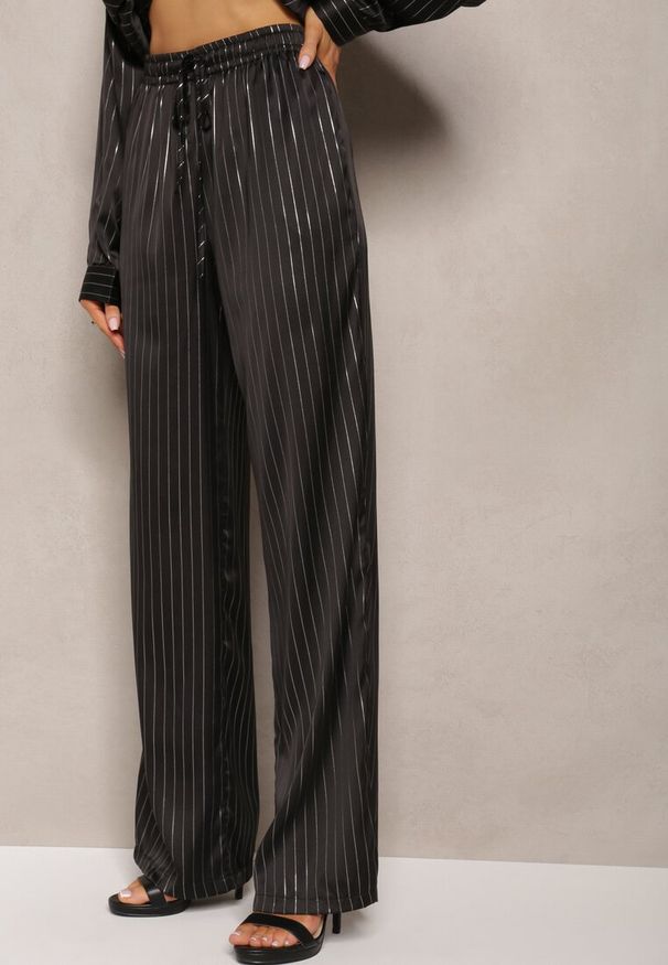 Renee - Czarne Szerokie Spodnie z Gumką w Talii i Błyszczącym Wzorem w Paski Zoyama. Kolor: czarny. Wzór: paski