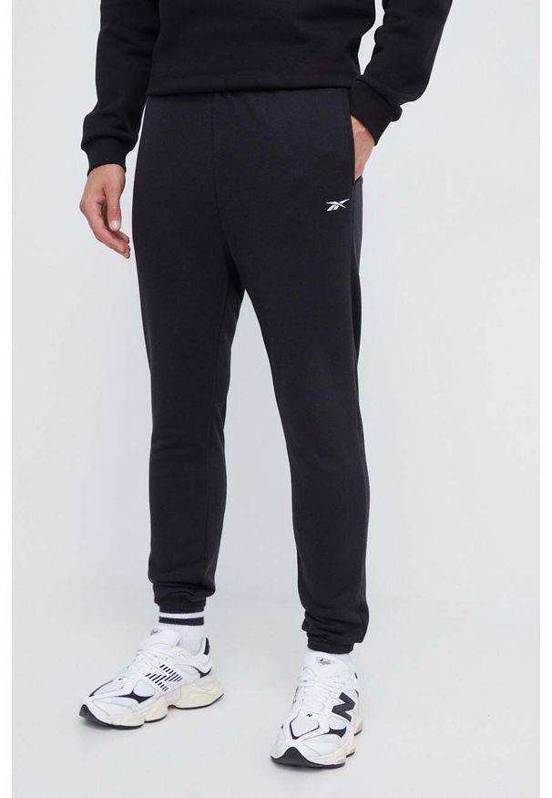 Reebok spodnie męskie kolor czarny gładkie. Kolor: czarny. Materiał: włókno, dzianina, materiał. Wzór: gładki