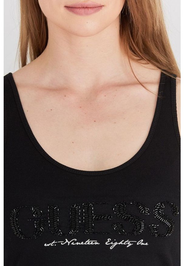 Guess - GUESS Czarny top damski z logo z koralików. Kolor: czarny. Materiał: bawełna. Wzór: nadruk