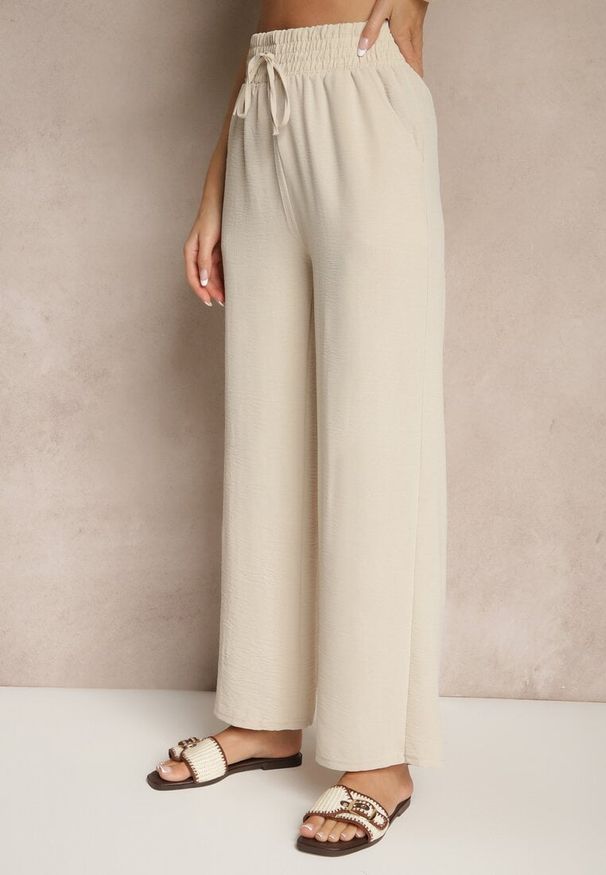 Renee - Beżowe Szerokie Spodnie High Waist z Gumką w Pasie Savimirae. Okazja: na co dzień. Stan: podwyższony. Kolor: beżowy. Styl: elegancki, casual
