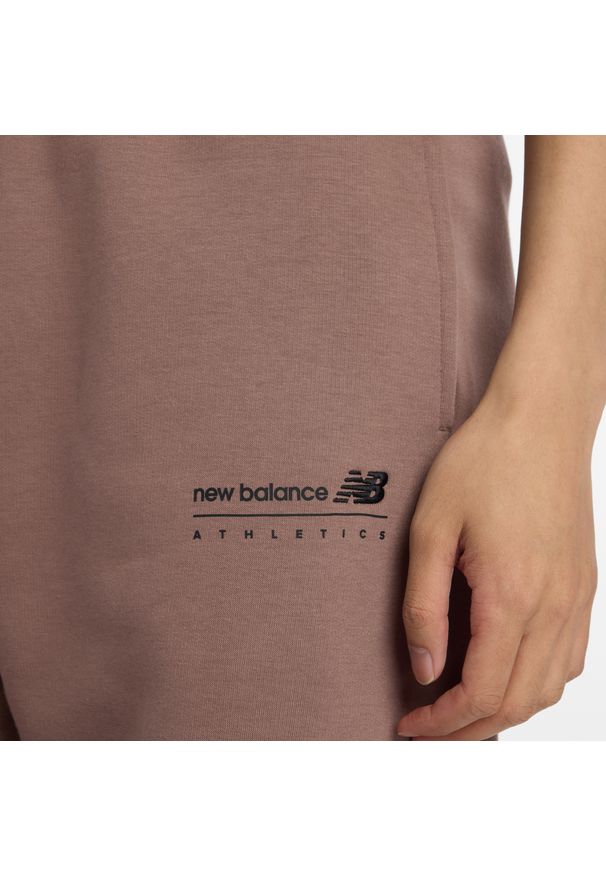 Spodnie męskie New Balance MP53508EAS – brązowe. Kolor: brązowy. Materiał: bawełna, dresówka, materiał, poliester. Wzór: aplikacja, napisy