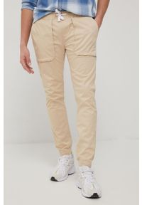 Tommy Jeans spodnie SCANTON męskie kolor beżowy joggery. Kolor: beżowy. Materiał: materiał, bawełna, tkanina. Wzór: gładki