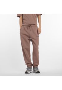 Spodnie męskie New Balance MP53508EAS – brązowe. Kolor: brązowy. Materiał: dresówka, materiał, poliester, bawełna. Wzór: aplikacja, napisy