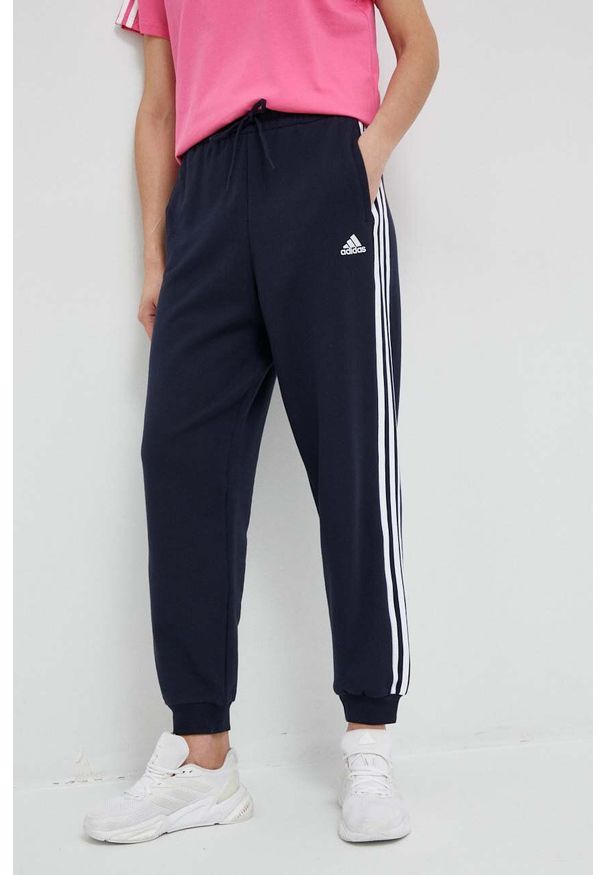Adidas - adidas spodnie dresowe bawełniane kolor granatowy wzorzyste. Kolor: niebieski. Materiał: bawełna, dresówka