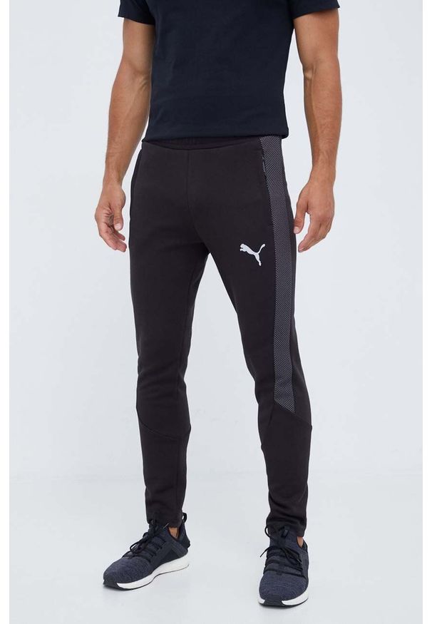Puma spodnie treningowe Evostripe kolor czarny z nadrukiem. Kolor: czarny. Materiał: skóra, materiał. Wzór: nadruk