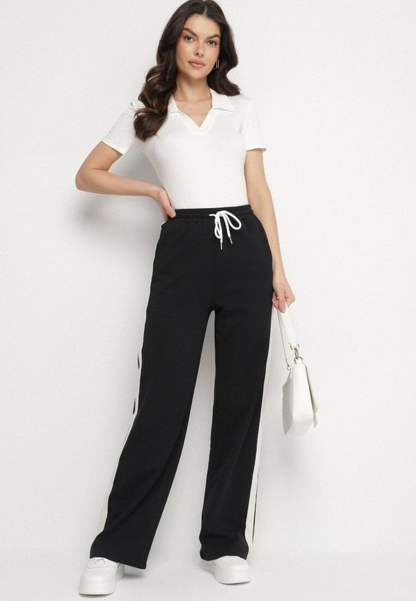 Born2be - Czarne Bawełniane Spodnie Dresowe o Szerokim Kroju z Lampasami Alarita. Okazja: na co dzień. Stan: podwyższony. Kolor: czarny. Materiał: dresówka, bawełna. Styl: sportowy, klasyczny, elegancki, casual