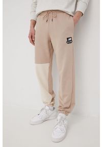 New Balance spodnie dresowe bawełniane męskie kolor beżowy z nadrukiem. Kolor: beżowy. Materiał: dresówka, bawełna. Wzór: nadruk