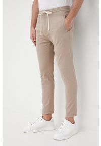 Drykorn spodnie męskie kolor beżowy joggery. Kolor: beżowy. Materiał: bawełna, tkanina. Wzór: gładki