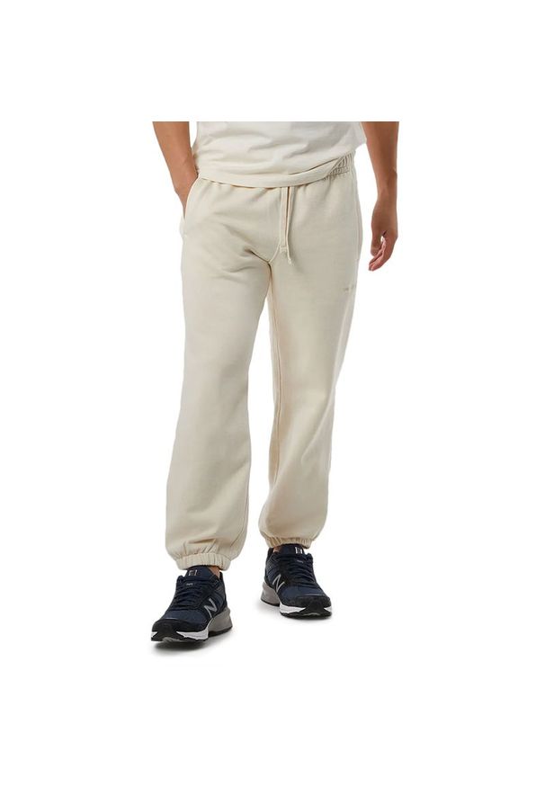 Spodnie dresowe New Balance MP23551GIE - beżowe. Kolor: beżowy. Materiał: dresówka