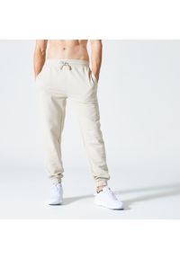 DOMYOS - Spodnie dresowe męskie Domyos Gym & Pilates 500 Essentials. Kolor: beżowy. Materiał: materiał, bawełna, poliester, elastan. Wzór: ze splotem. Sport: joga i pilates #1