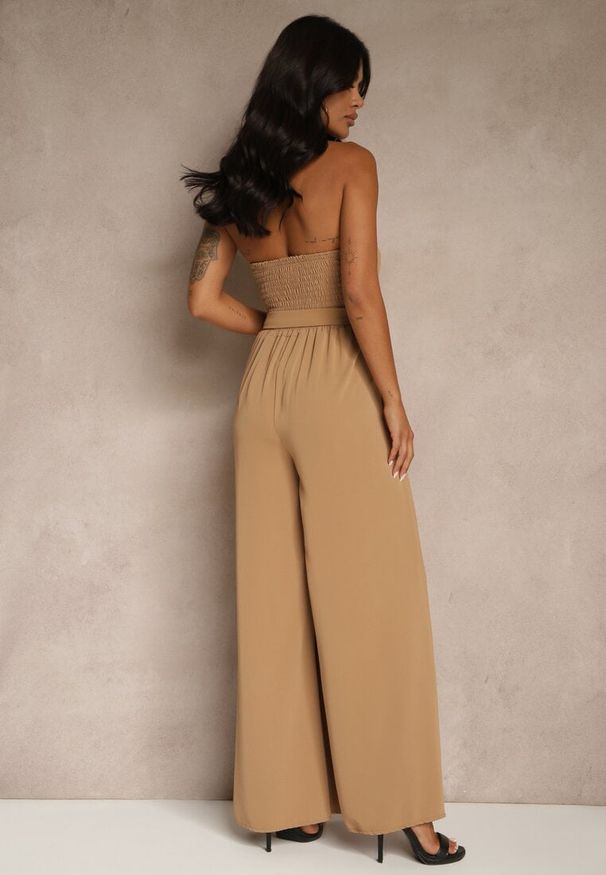 Renee - Ciemnobeżowy Kombinezon Koktajlowy Ozdobiony Paskiem z Metaliczną Klamrą Zermira. Okazja: na imprezę, na co dzień. Kolor: beżowy. Wzór: aplikacja. Styl: wizytowy