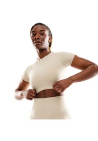 SIROKO - Damska bezszwowa sportowa koszulka crop top z krótkim rękawem Fitness Siroko S. Kolor: beżowy. Materiał: materiał, tkanina. Długość rękawa: krótki rękaw. Długość: krótkie. Sport: fitness
