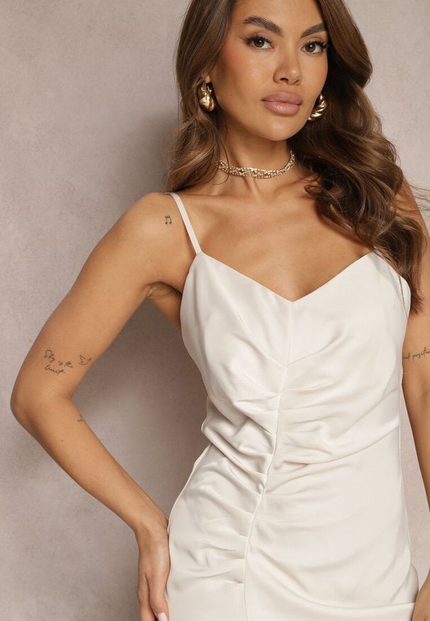 Renee - Jasnobeżowa Sukienka z Marszczonej Satyny z Regulowanymi Ramiączkami i Rozcięciem Caraluma. Okazja: na randkę, na imprezę. Typ kołnierza: dekolt w serek. Kolor: beżowy. Materiał: satyna. Długość rękawa: na ramiączkach. Styl: elegancki. Długość: midi