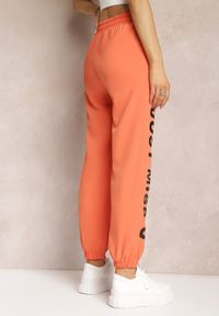Renee - Pomarańczowe Dresowe Spodnie z Dużym Napisem z Boku Nogawki Karına. Kolor: pomarańczowy. Materiał: dresówka. Wzór: napisy #2