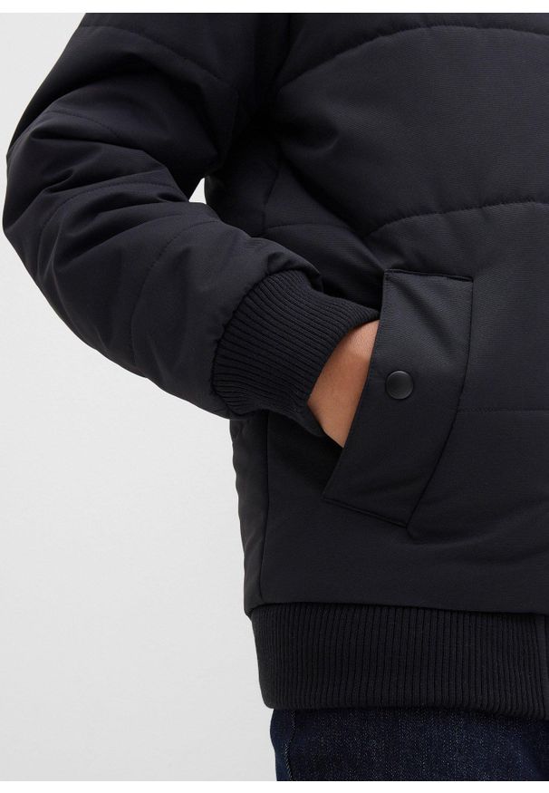 bonprix - Zimowa kurtka pikowana o kroju bomberki z kapturem. Typ kołnierza: kaptur. Kolor: czarny. Materiał: prążkowany. Sezon: zima