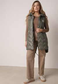 Born2be - Zielona Przejściowa Kamizelka Pikowana o Długim Kroju z Kapturem i Naszywką Harmaste. Okazja: na co dzień. Typ kołnierza: kaptur. Kolor: zielony. Materiał: jeans. Długość: długie. Wzór: aplikacja. Styl: casual #2