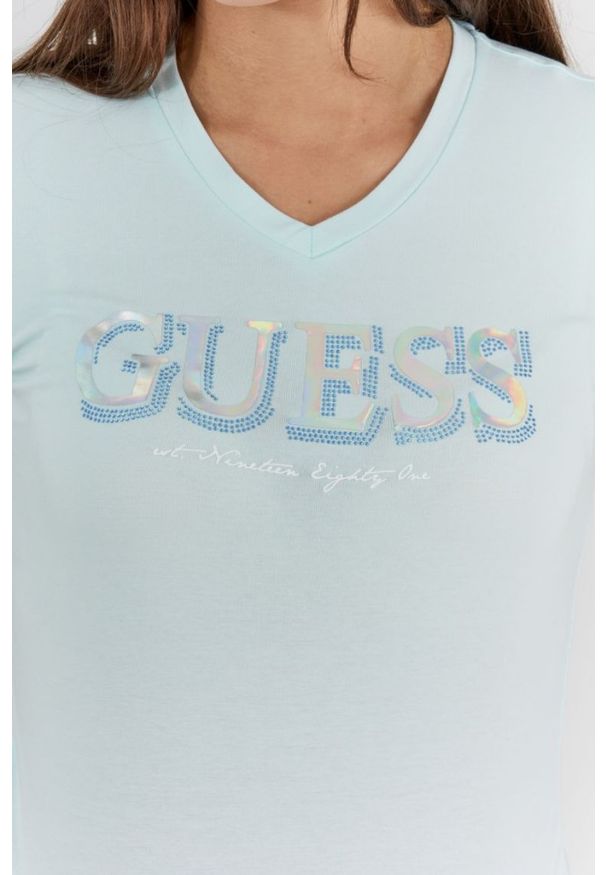 Guess - GUESS Błękitny t-shirt damski z metalicznym logo i cyrkoniami. Typ kołnierza: dekolt w serek. Kolor: niebieski. Materiał: bawełna