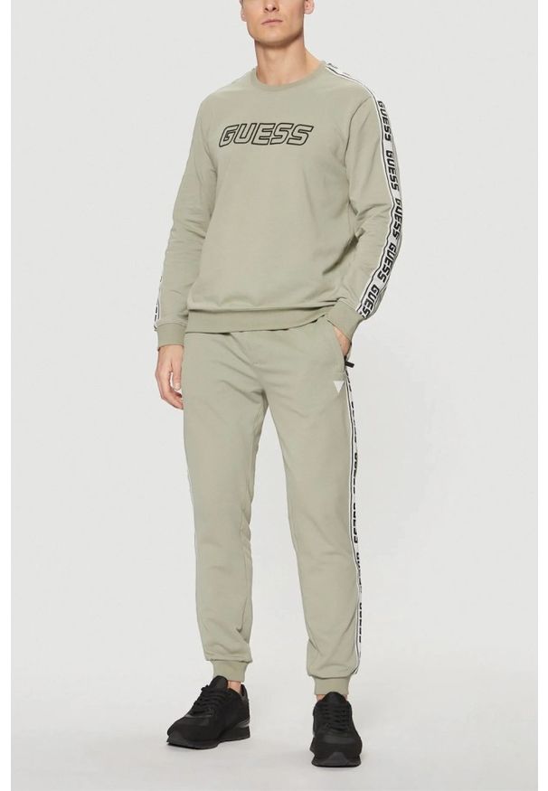 Guess - GUESS Zielone męskie spodnie dresowe z lampasami New Arlo. Kolor: zielony. Materiał: dresówka